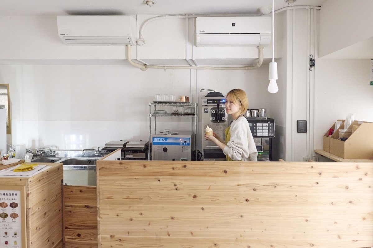 Staff member holding a soft serve at the wooden counter