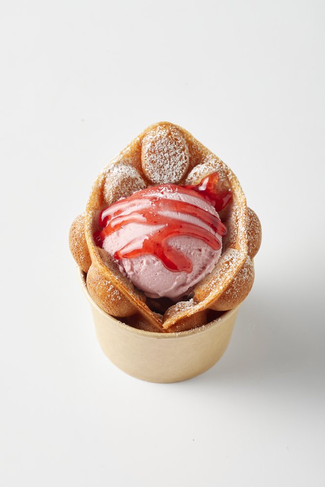 Bubble waffle cup with a scoop of pink gelato and red sauce